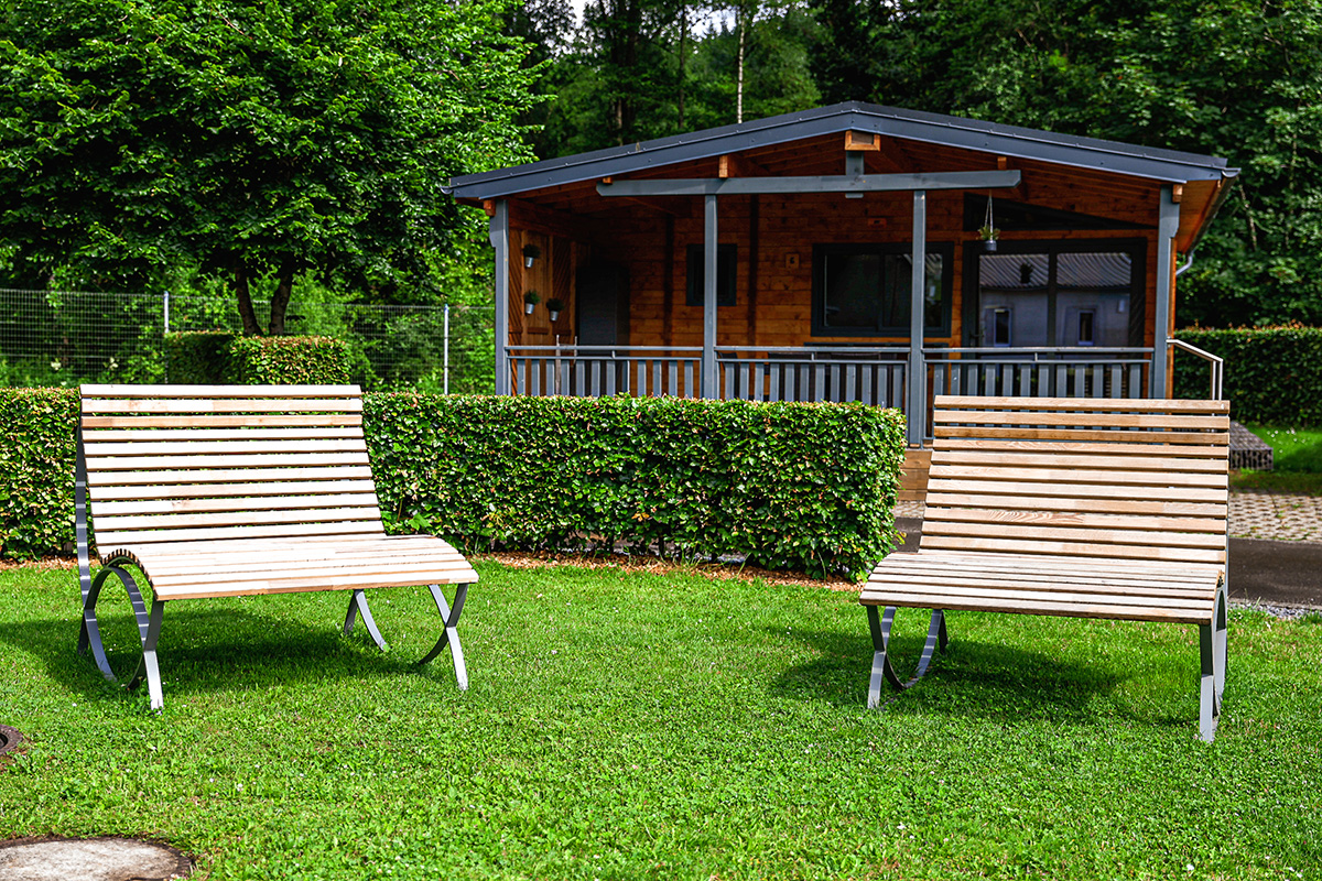 Chalet Ardenne from outside with lawn and benches at Camping Kaul in Wiltz